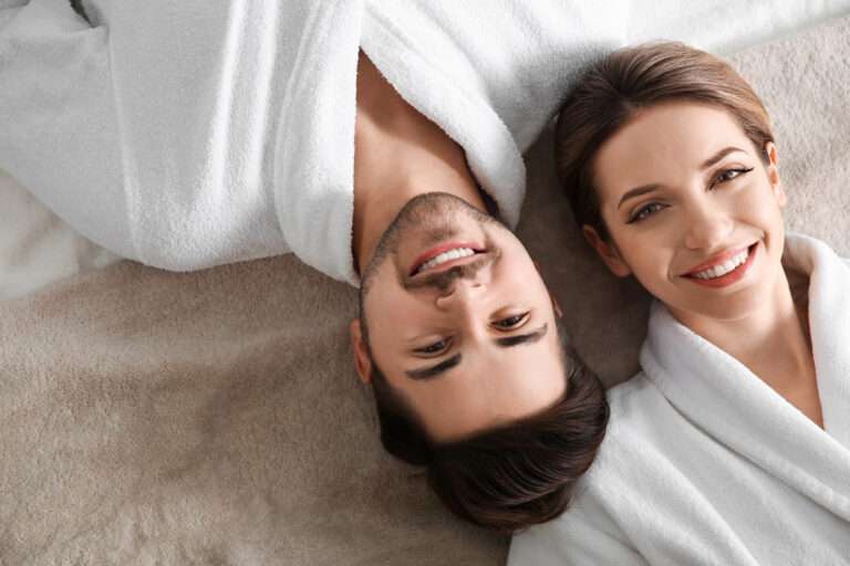 Happy young couple wearing bathrobes, top view. Visit to spa salon